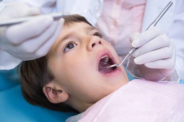 Dentist holding equipment while examining boy — Stock Photo, Image