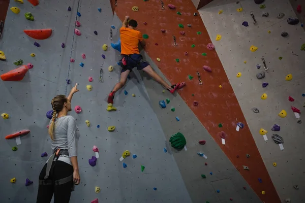 Mujer instruyendo atleta en pared de escalada — Foto de Stock