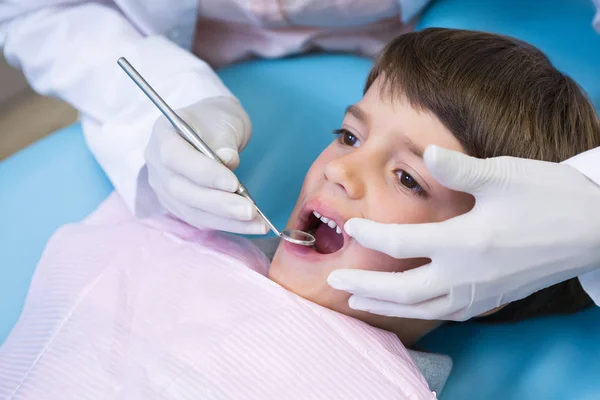 Стоматолог держит оборудование во время осмотра мальчика — стоковое фото