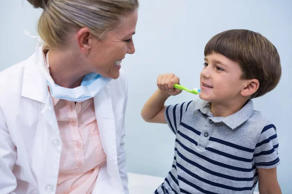 Niño sosteniendo el cepillo de dientes mientras mira al dentista — Foto de Stock