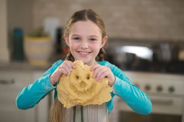 Smiling girl holding dough in kitchen — Stock Photo, Image