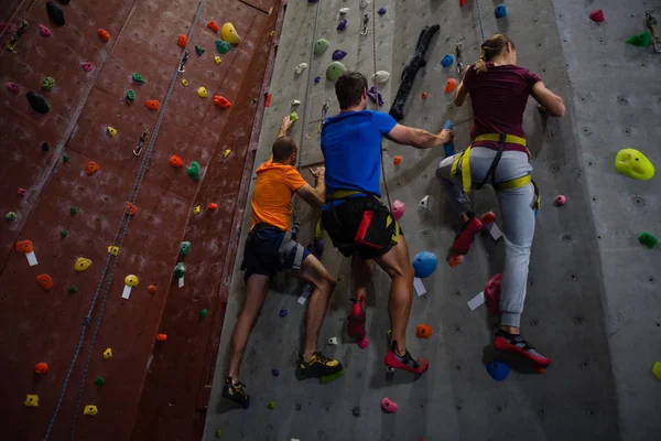 Athletes and trainer climbing wall in gym — Stock Photo, Image