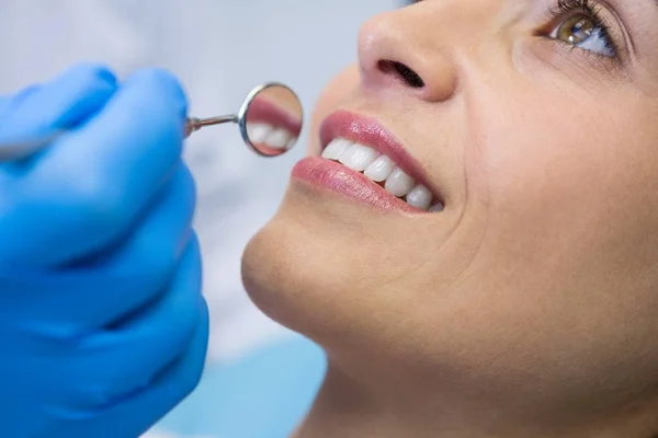 Dentist holding angled mirror by smiling woman — Stock Photo, Image