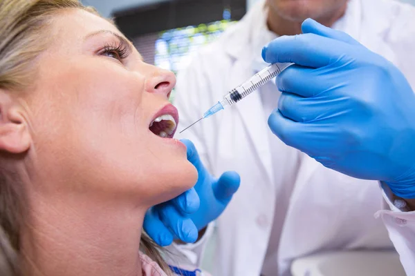 Dokter gigi memegang jarum suntik oleh pasien — Stok Foto