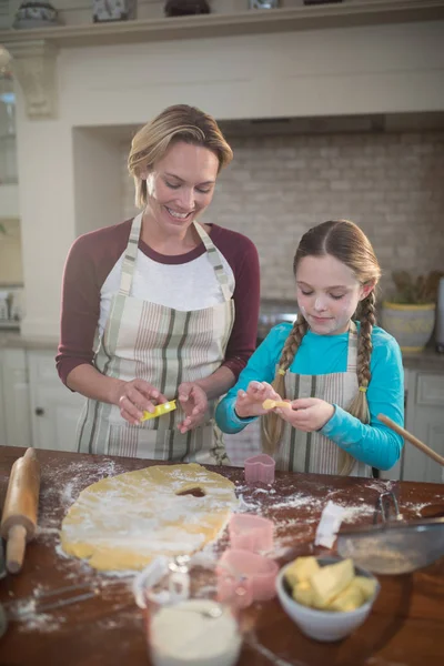 Mother and daughter preparing cookies in kitchen — Stock Photo, Image