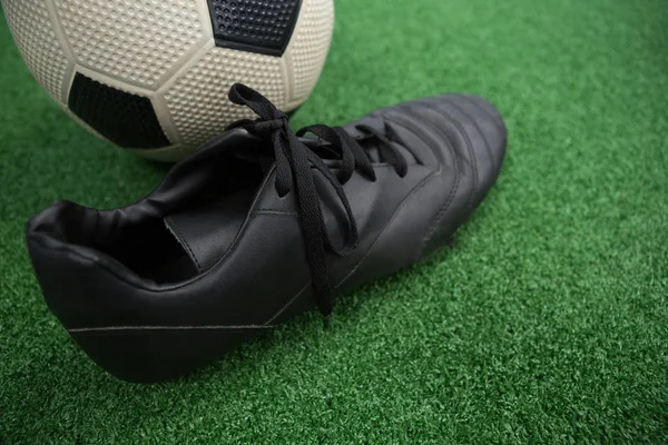 Football and cleats on artificial grass — Stock Photo, Image