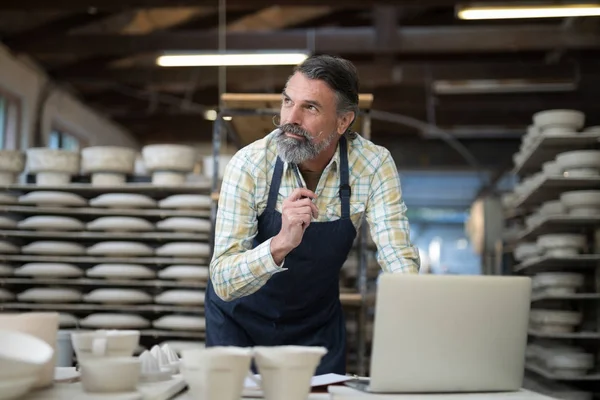 Alfarero masculino reflexivo que trabaja en worktop — Foto de Stock