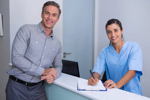 Médico segurando caneta de pé pelo homem na mesa — Fotografia de Stock