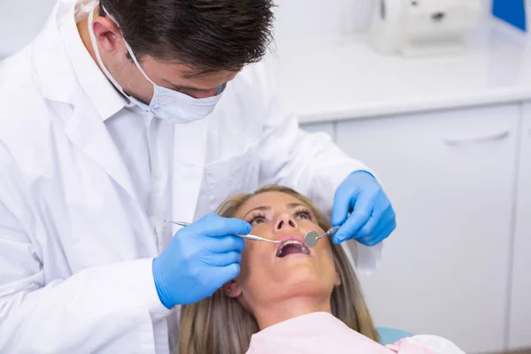 Dentista examinando mujer en clínica dental — Foto de Stock