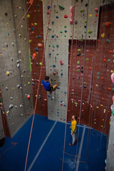 Male trainer hanging on rope talking to woman — Stock Photo, Image