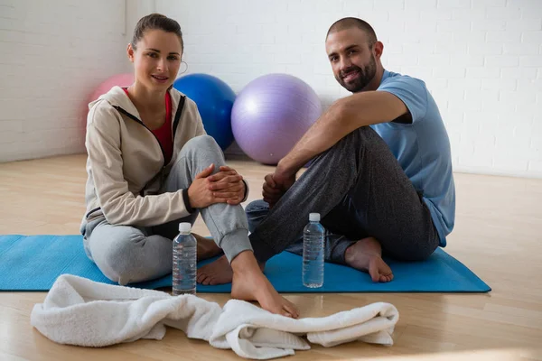 Student with instructor relaxing in yoga studio — Stock Photo, Image