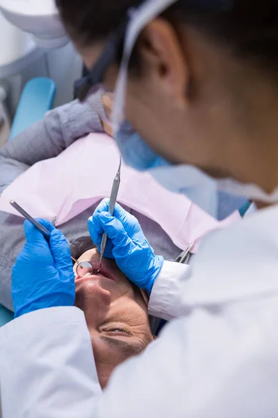 Dokter geven tandheelkundige behandeling aan man bij kliniek — Stockfoto