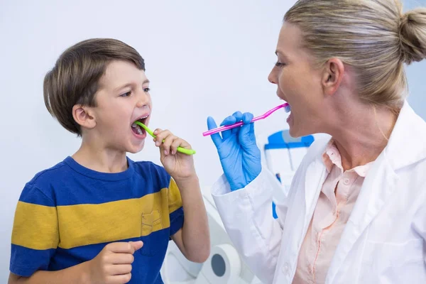 Dentista y niño cepillarse los dientes contra la pared — Foto de Stock