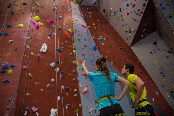 Athletes interacting while standing by climbing wall — Stock Photo, Image