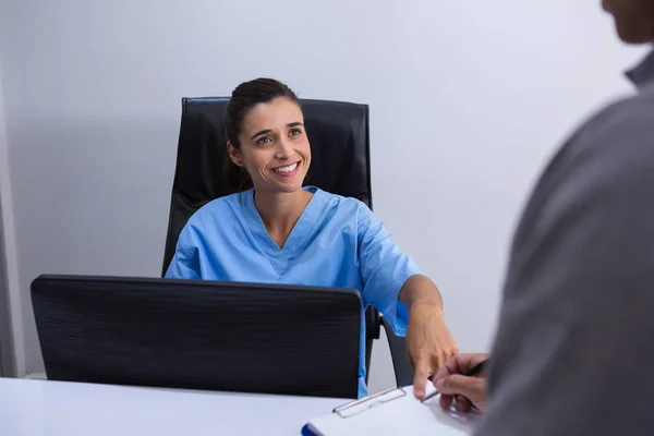 Läkare som interagerar med patienten vid skrivbord — Stockfoto