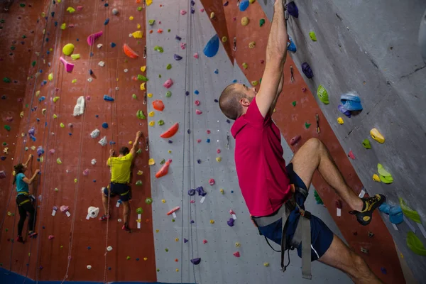 Confident athletes and trainer climbing wall in club — Stock Photo, Image