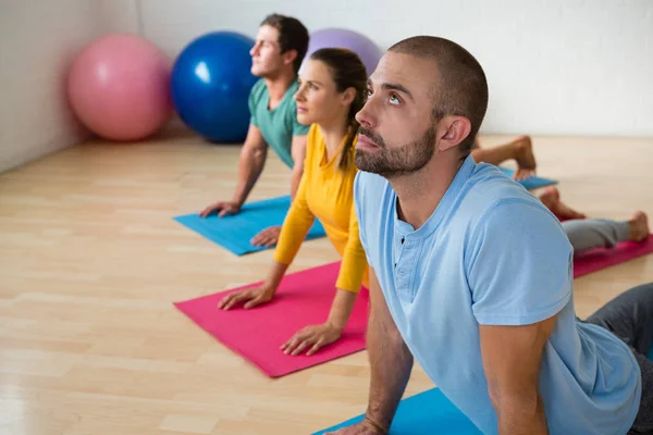 Instruktör vägledande studenter i att öva cobra pose — Stockfoto