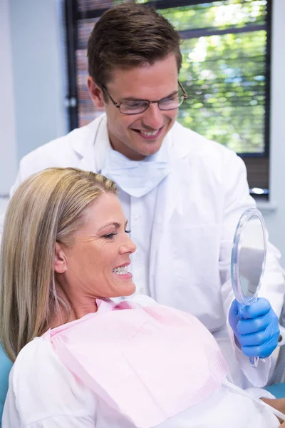 Dentista mostrando espejo a paciente sonriente —  Fotos de Stock