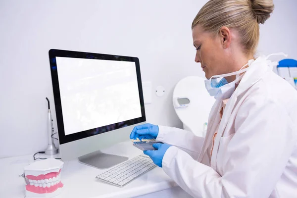 Dentist working while sitting by computer — Stock Photo, Image