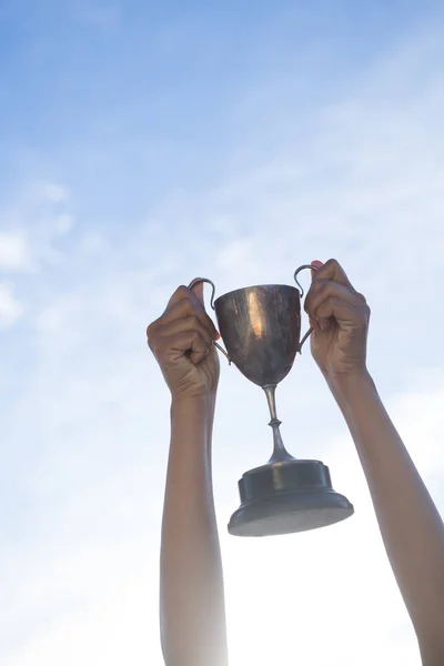 Hand holding a trophy against sky and cloud — Stock Photo, Image