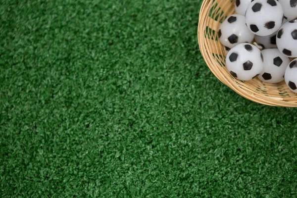 Bolas de futebol em cesta de vime na grama artificial — Fotografia de Stock