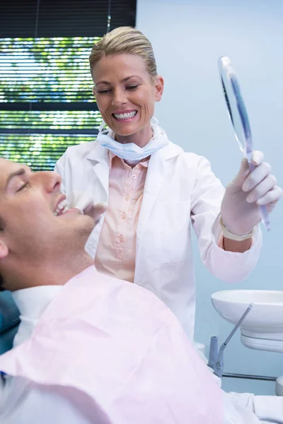 Dentist showing mirrior to patient — Stock Photo, Image