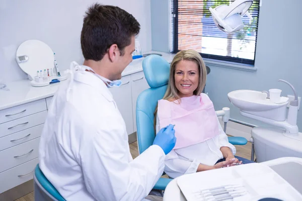 Улыбающийся пациент обсуждает с дантистом — стоковое фото