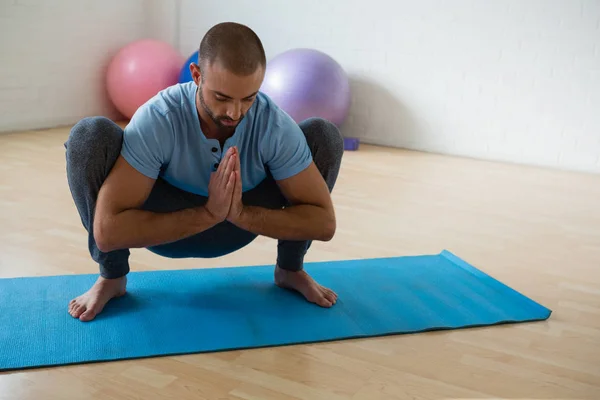 Yoga instructor practicing garland pose in club — Stock Photo, Image