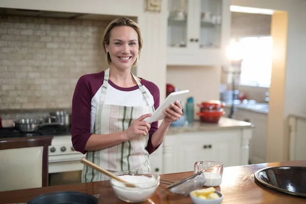 Woman using digital tablet while preparing cookies — Stock Photo, Image