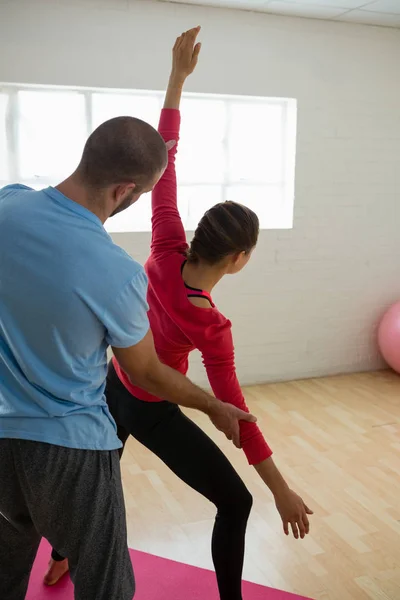Yoga instructor assisting student in exercising — Stock Photo, Image