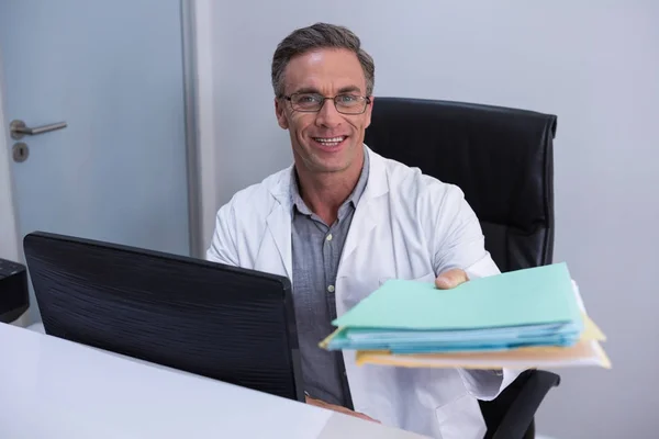 Dentist holding file while sitting by computer — Stock Photo, Image