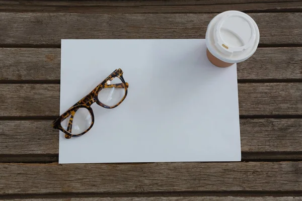 Óculos, vidro descartável e papel em branco — Fotografia de Stock