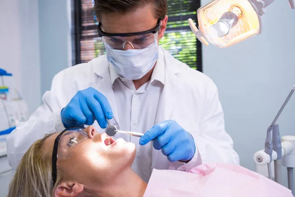 Tandläkare Hållande verktyg samtidigt undersöka kvinna — Stockfoto
