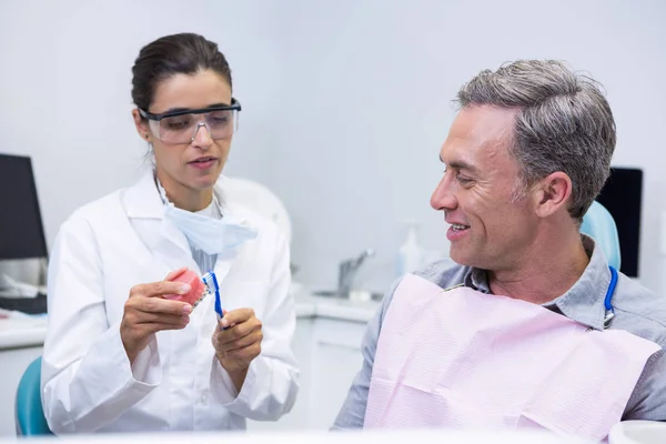 Dentist teaching man brushing teeth — Stock Photo, Image