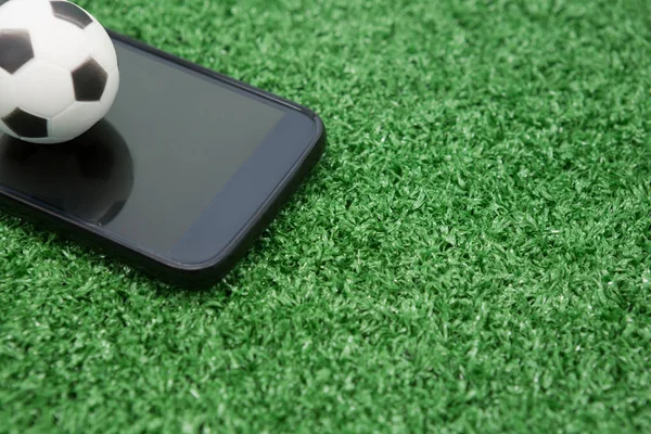 Piłka nożna i telefon komórkowy na sztucznej trawie — Zdjęcie stockowe