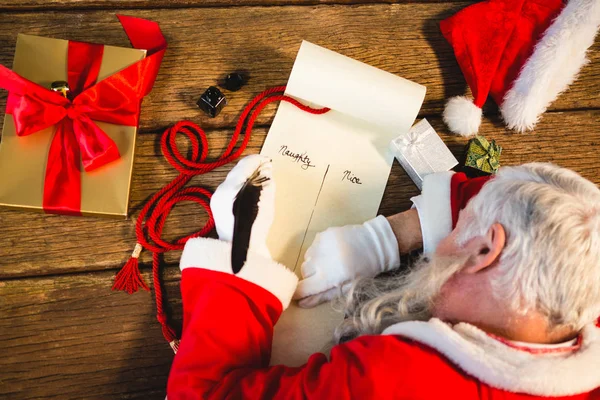 Weihnachtsmann schläft am Tisch, während er einen Brief mit einem Federkiel schreibt — Stockfoto