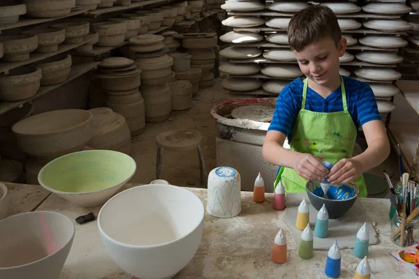 Menino pintando uma tigela na loja de cerâmica — Fotografia de Stock