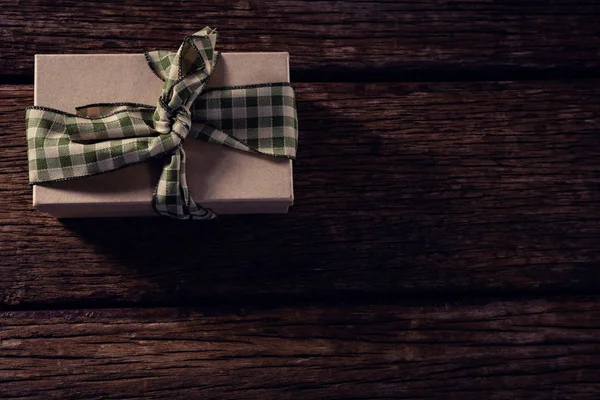 Wrapped gift box on wooden plank — Stock Photo, Image