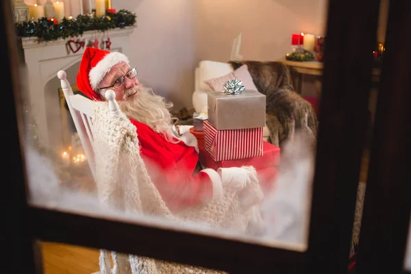 Noel Baba hediye kutuları yığınıyla oturan — Stok fotoğraf