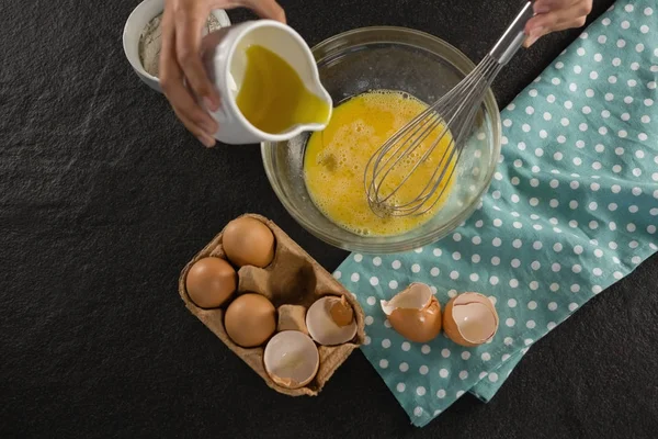 Woman adding oil into beaten eggs — Stock Photo, Image