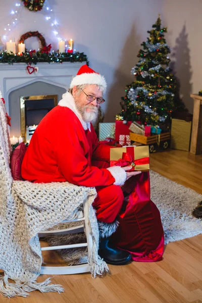 Santa claus att sätta presenterar i christmas väska — Stockfoto