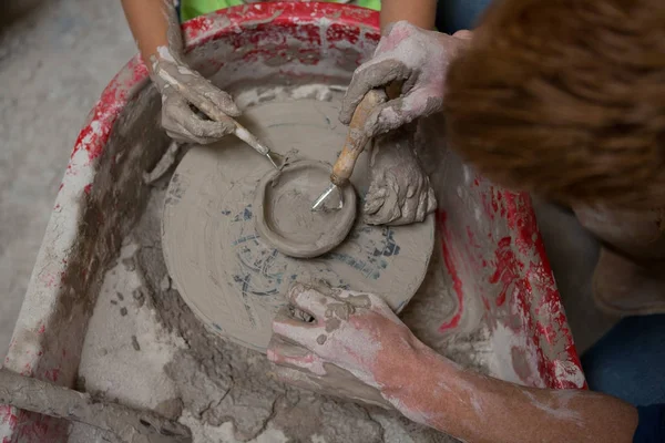 Mand pottemager hjælpe pige i støbning et ler - Stock-foto