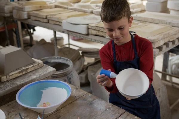 Мальчик украшает миску акварелью — стоковое фото