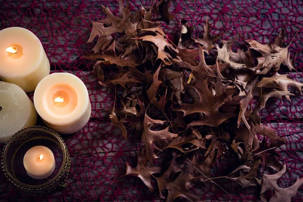 Lit velas e folhas secas na mesa — Fotografia de Stock