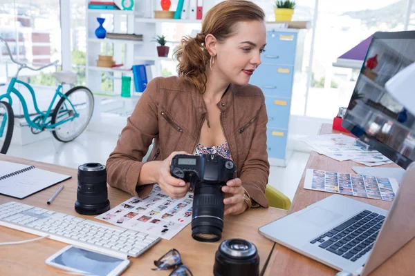 Executivo Feminino Segurando Câmera Digital Enquanto Olha Para Laptop Escritório — Fotografia de Stock