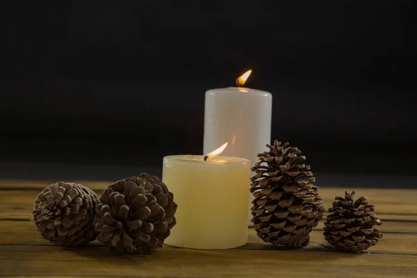 Pine cones with illuminated candles on table Stock Photo