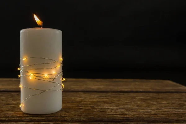 Luces de cuerda iluminadas envueltas en una vela encendida — Foto de Stock