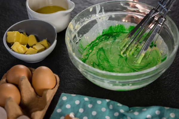 Green color batter whisked in a bowl — Stock Photo, Image