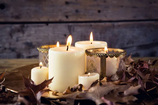 Aangestoken kaarsen en droge bladeren op tafel — Stockfoto