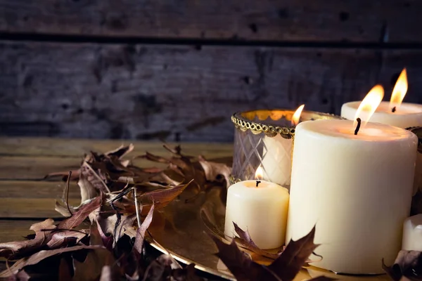 Lit velas e folhas secas na mesa — Fotografia de Stock